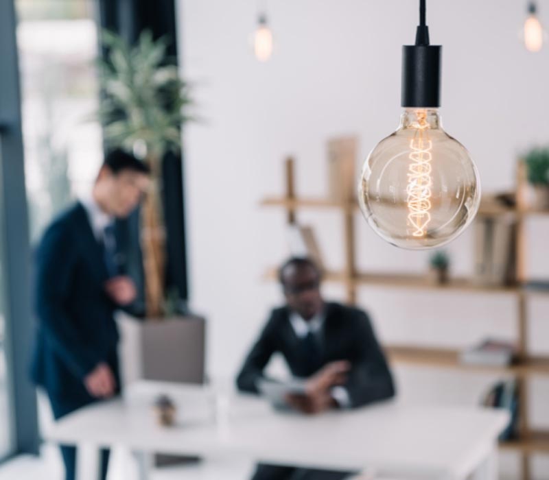 Lit lightbulb with business men in background